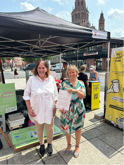 Prof. Dr.-Ing. Susanne Hartard und rheinland-pfälzische Klimaschutzministerin Katrin Eder vor Messestand auf öffentlichem Platz in Mainz.