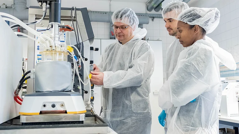 Personen in Reinraumkleidung, Haarschutz, Handschuhe im Labor