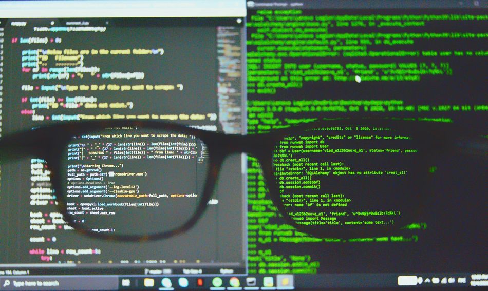 Brille vor PC Bildschirm mit Codezeilen.
